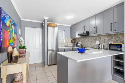 a kitchen with white cabinets and a refrigerator at The Waves 302 in Cape Town