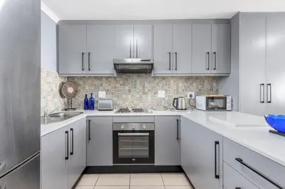 a white kitchen with white cabinets and appliances at The Waves 302 in Cape Town