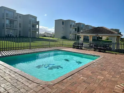 a swimming pool in front of some apartment buildings at Seaside Serenity in Hermanus