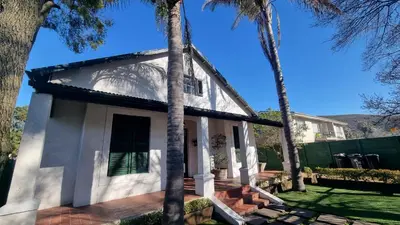a white house with palm trees in front of it at Château Naudé in Stellenbosch Free Secure Parking in Stellenbosch