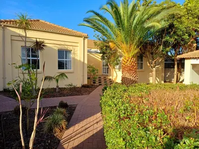 a house with palm trees and a sidewalk at Somerset Garden Route Apartments & Wellness in Somerset West