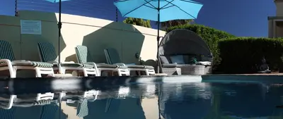a group of chairs and an umbrella next to a pool at Somerset Garden Route Apartments & Wellness in Somerset West
