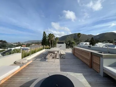 a deck with a table and a kitchen on a house at The Hermanus Retreat in Hermanus