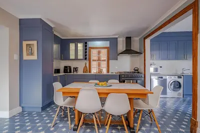 a kitchen with blue cabinets and a wooden table and chairs at Blue Bell in Hermanus