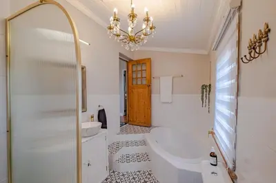 a bathroom with a chandelier and a tub and a sink at Blue Bell in Hermanus