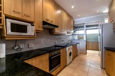 a kitchen with wooden cabinets and a microwave at Bayview 307 in Hermanus