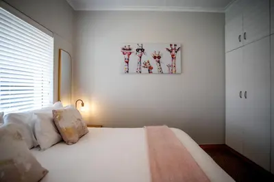 a bedroom with a white bed and a painting on the wall at Bayview 307 in Hermanus