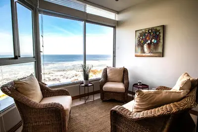 a living room with two chairs and large windows at Bayview 307 in Hermanus