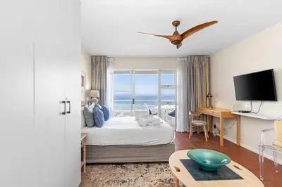 a bedroom with a bed with a view of the ocean at Sea Spray A410 in Cape Town