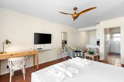 a room with a bed and a desk and a tv at Sea Spray A410 in Cape Town