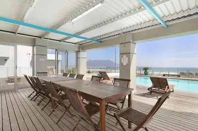 a dining room with a table and chairs and a pool at Sea Spray A410 in Cape Town