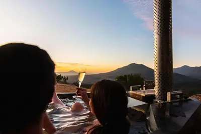 a man and a woman in a hot tub with a glass of wine at Heuwels in Blauwvlei