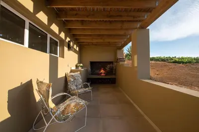 a porch with two chairs and a fireplace at Heuwels in Blauwvlei