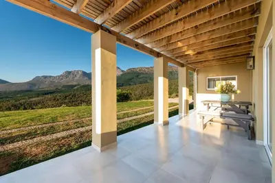 a patio with a table and a view of mountains at Heuwels in Blauwvlei