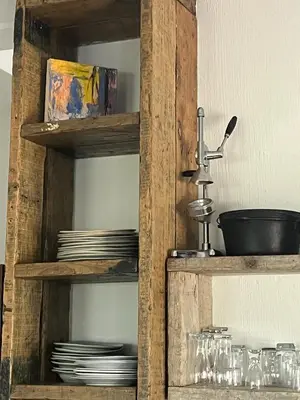 a wooden cabinet with plates and dishes in it at Sublime modern beachfront villa in paradise in Hawston