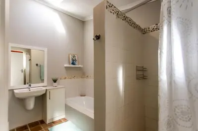a bathroom with a tub and a sink and a shower at Plaisir du Cap in Hermanus