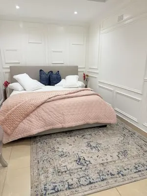 a bedroom with a bed with a pink blanket and a rug at Three Bedroom Apartment in Cape Town