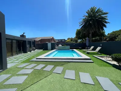 a backyard with a swimming pool and grass at Three Bedroom Apartment in Cape Town