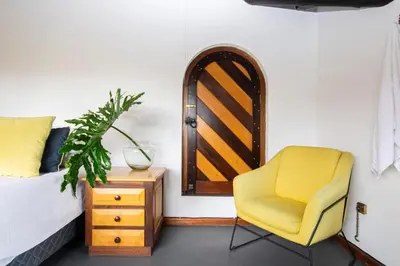 a bedroom with a bed and a yellow chair at Mountain View and Vineyard View in Suider-Paarl