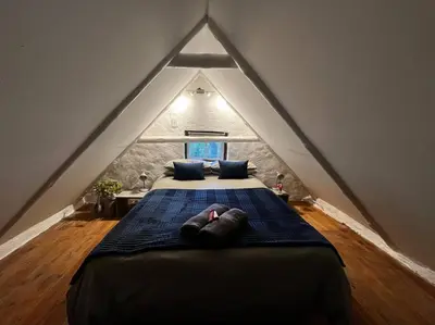 a person laying on a bed in a attic at Mouse House Greyton - tiny home living in Greyton
