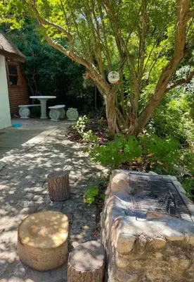 a garden with stools and a tree and a house at Mouse House Greyton - tiny home living in Greyton