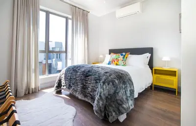 a white bedroom with a bed and a window at House La Gratitude - secure parking in Stellenbosch