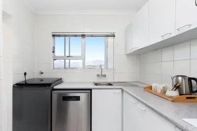 a white kitchen with a sink and a dishwasher at Odeon Towers 1102 in Cape Town