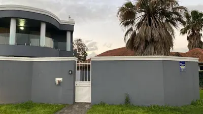 a house with a gate and a palm tree at KBJ House in Cape Town