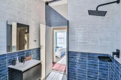 a bathroom with a sink and blue tiles at Mocha Bay House by the Sea in Bettyʼs Bay