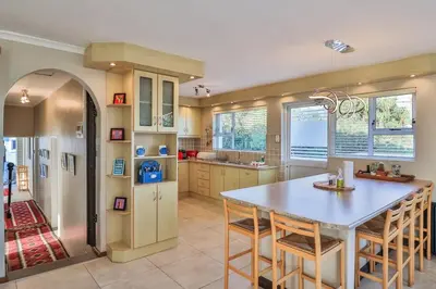 a kitchen with a table and some chairs in it at Mocha Bay House by the Sea in Bettyʼs Bay