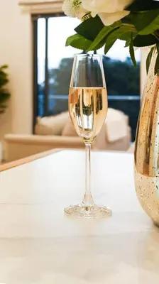 a glass of wine sitting on a table with a vase at 308 on Titanium in Strand