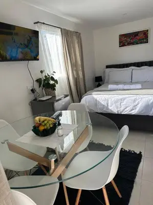 a room with a glass table and chairs and a bed at Cozy Private Studio in Cape Town