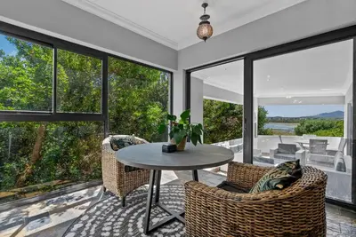 a living room with a table and chairs and windows at Flamingo Bay Manor in Fisherhaven