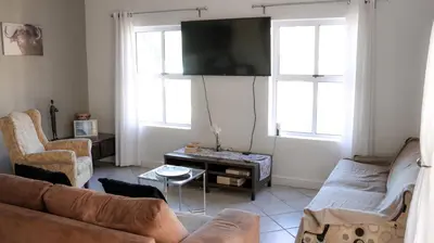 a living room with a couch and two windows at Somerset Wineland Apartments & Wellness in Somerset West