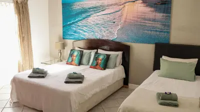 a bedroom with two beds and a painting on the wall at Somerset Wineland Apartments & Wellness in Somerset West