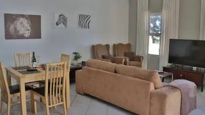 a living room with a couch and a television at Somerset Wineland Apartments & Wellness in Somerset West