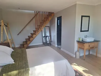 a bedroom with a bed and a sink and a staircase at Governor's nest in Cape Town