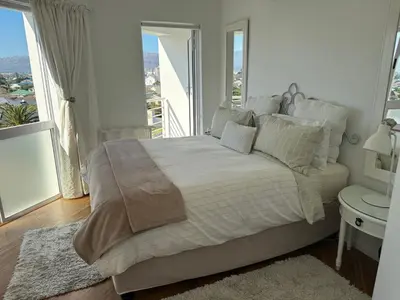 a white bedroom with a large bed and a window at Clouds in Strand