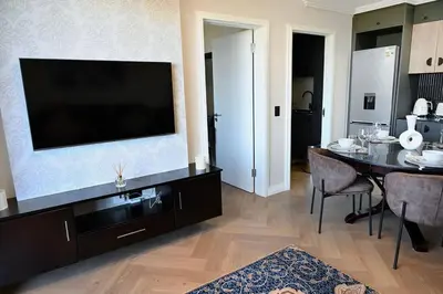 a living room with a television and a dining table at BGS Luxury -Two-bed -Nine Palms in Cape Town