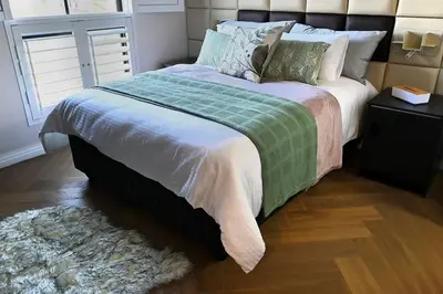 a bedroom with a large bed with pillows and a rug at BGS Luxury -Two-bed -Nine Palms in Cape Town
