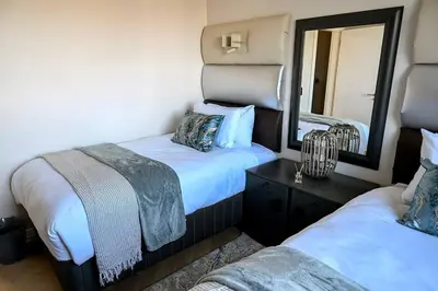 a bedroom with two beds and a mirror at BGS Luxury -Two-bed -Nine Palms in Cape Town