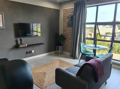 a living room with a couch and chairs and a tv at Ultra-Modern Studio Apartment in Table View