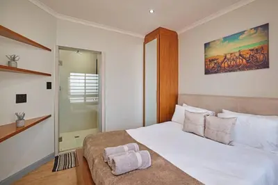 a bedroom with a white bed with a towel on it at Modern Cape Town Beach Apartment in Cape Town