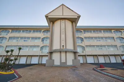 a building with a clock tower in front of it at Modern Cape Town Beach Apartment in Cape Town