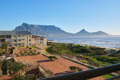 a view of the beach with mountains in the background at Modern Cape Town Beach Apartment in Cape Town