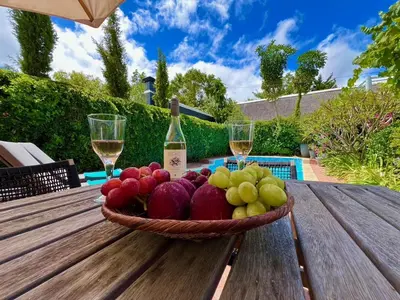 a bowl of fruit on a wooden table with wine glasses at Franschhoek Three Bedroom Cottage On Dirkie Uys in Franschhoek