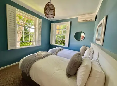 a blue bedroom with a bed and two windows at Franschhoek Three Bedroom Cottage On Dirkie Uys in Franschhoek