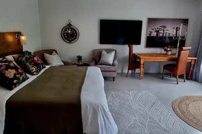 a bedroom with a bed and a table and a tv at C'est la Vie 1 in Franschhoek