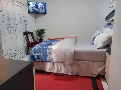 a bedroom with a bed with a tv on the wall at One Bedroom Apartment in Cape Town