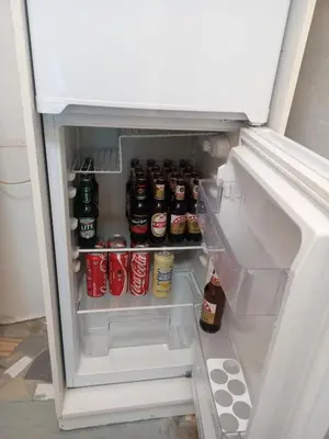 an open refrigerator filled with bottles and cans of soda at One Bedroom Apartment in Cape Town